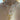 Close-up of a layered necklace look featuring four gold and pearl necklaces. The top choker is made of white pearls with a central gold heart bead and a sparkly gold letter “S” charm. Below it hangs a delicate gold necklace with a cube pendant featuring a gold heart. The lowest necklace showcases an ornate gold design with two hands holding a ring, a heart-shaped locket, and a dangling mini heart charm.