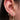 Close-up of an ear wearing a celestial-themed earring set, including a rose quartz heart stud with a dangling crescent moon, a small crystal hoop, and a larger gold hoop with a sparkling crescent moon charm.