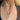 A woman wears layered silver necklaces; one with pearls, a heart charm, letters spelling "MEL," and a pendant with a pink heart. Her top is dark-colored.
