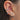 Close-up of an ear with multiple earrings including floral designs.