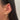 Close-up of an ear adorned with three gold earrings. The earrings feature a heart, star, and diamond shapes, exuding an elegant and trendy vibe.