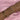A forearm styled with multiple delicate gold-toned bracelets, featuring designs with pearls, dainty crystals, star and cross charms, and chain links, all set against a soft pink satin background.