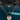 Close-up of three layered gold necklaces hanging in sunlight. The top necklace features a chunky paperclip chain with a pavé carabiner clasp. The middle necklace displays a custom name pendant in Arabic script, and the bottom necklace showcases a circular pendant with concentric layers of baguette and round-cut stones, all glowing against a turquoise poolside backdrop.