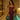 Elegant woman in fitted burgundy corset dress with black mesh detailing, wearing a gold cross necklace, posing by an indoor plunge pool