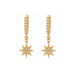 A pair of gold huggie hoop earrings with a vertical channel set with small clear stones and a dangling gold starburst charm, shown on a plain white background.