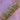 A forearm adorned with numerous gold and silver bangles, featuring heart and star motifs, against a pink fabric background, exuding elegance and style.