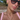 Woman wearing sunglasses and a pink top with layered necklaces outdoors.