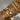 Close-up of a hand wearing multiple gold bracelets with various designs on a neutral background.