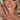 Blonde woman smiling in glam makeup wearing a white lace top and a sparkly gold cross necklace, styled with soft curls