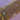 Arm wearing multiple gold bracelets with various designs, including pearls, beads, and crystals, set against a soft lavender background. Elegant and classic.