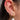 Curated gold earring stack featuring pearl drop hoop, cubic zirconia huggies, cartilage hoop and dainty helix dangle piercing on a woman's ear