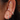 Close-up of three gold huggie hoop earrings with cubic zirconia and star detailing on a woman's ear, styled for a stacked piercing look