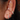 Close-up of three gold huggie hoop earrings with cubic zirconia and star detailing on a woman's ear, styled for a stacked piercing look