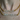 Close-up of a person wearing two bold gold chain necklaces with diamond-encrusted name pendants. The top necklace spells “NATALIA” and the bottom spells “BINKYBELLE.” The chains rest against bare skin, with a turquoise background slightly visible.