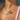 Close-up of a woman wearing two balloon-style letter necklaces. The top gold necklace spells “NATALIA,” and the lower silver necklace spells “BINKY BELLE.” She is wearing a white swimsuit with red scalloped trim near a poolside setting.
