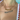 Close-up of a woman wearing two balloon-style letter necklaces. The top gold necklace spells “NATALIA,” and the lower silver necklace spells “BINKY BELLE.” She is wearing a white swimsuit with red scalloped trim near a poolside setting.