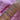 A forearm adorned with elegant bracelets featuring heart and circle designs, some encrusted with crystals, resting on a pink fabric background.