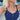 A close-up lifestyle shot of a blonde woman wearing a layered silver necklace set with a teardrop pendant, small star charms, and a turquoise accent, paired with a navy blue tank top.
