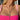 Close-up of a person wearing a pink top with a necklace.