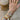 Hand wearing multiple gold bracelets and rings with a wicker chair in the background