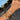 Hand wearing multiple gold bracelets with various charms against a blurred outdoor background