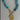 Necklace with turquoise beads and a gold ammonite pendant on a gray background