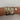 A stack of multiple charm bracelets in gold, silver, and black metals, decorated with heart charms, rhinestone details, and a small engraved heart tag, shown worn on a wrist against a plain light background.