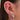 Close-up of an ear with multiple diamond and pink gemstone earrings.