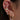 Close-up of an ear with multiple gold and pink earrings.
