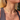 Close-up of a woman wearing gold necklaces and earrings with a blurred background