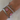 Silver bracelet with 'Jessica' and pink flower charms on a wrist against a neutral background