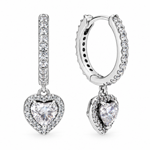 A pair of silver huggie hoop earrings with a vertical bar studded with small clear stones and a dangling heart-shaped clear gemstone surrounded by a halo, shown on a white background.