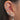 Close-up of an ear with multiple silver earrings and rings.