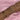 A forearm styled with multiple delicate gold-toned bracelets, featuring designs with pearls, dainty crystals, star and cross charms, and chain links, all set against a soft pink satin background.