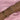 A wrist adorned with multiple gold and rose gold bracelets, featuring delicate chain styles, pearls, crystals, star and cross charms, all set against a soft pink satin background.