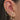 Close-up of an ear with multiple gold and pink earrings.