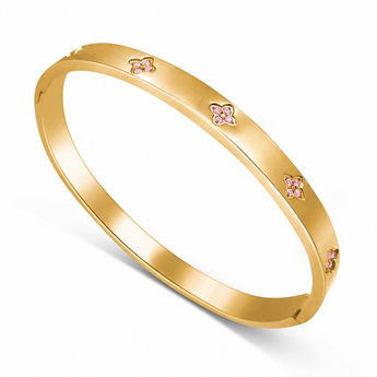 A polished yellow gold bangle bracelet with three small pink floral motifs set along the outer band, shown on a clean white background.