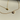 Two delicate gold necklaces displayed on a cream surface, one featuring a small heart pendant with a single clear stone, and the other showcasing a floral clover pendant encrusted with sparkling crystals.