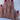A hand with burgundy nails wearing gold and diamond rings on every finger, resting on a white satin fabric, conveys elegance and luxury.