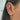 A detailed close-up of a woman's ear showcasing a stylish arrangement of gold and crystal earrings and cuffs. The ear features a dangling gold star charm in the upper cartilage, multiple cuffs with embedded gems, a small crystal cluster on the helix, and several sparkling hoops and studs. The standout piece is a drop earring with a gold-framed heart-shaped crystal at the lobe. The woman's straight dark hair frames the look on a softly lit background.
