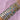 A forearm adorned with numerous gold and silver bracelets featuring various designs, hearts, and gems on a soft pink backdrop, conveying elegance and abundance.