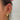 A chic gold ear stack featuring celestial-inspired jewellery, including a thick hoop with star embellishments, crystal-studded huggies, and a chain-drop earring with star charms. The look is elevated with layered cuffs and a crystal-link chain connecting upper ear piercings for a dreamy, constellation effect.