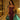 Elegant woman in fitted burgundy corset dress with black mesh detailing, wearing a gold cross necklace, posing by an indoor plunge pool