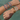 Close-up of a wrist with multiple colorful bracelets against a blurred natural background