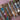 Stacked silver bangles with multicoloured enamel hearts, baguette diamonds, Roman numerals, and floral accents on a pink backdrop – trending bracelet stack.