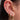 Stacked gold earrings featuring a mix of pavé huggies, dainty studs and a star charm drop, styled on a dark-haired model with multiple piercings
