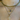 Layered gold necklaces featuring a sparkly snake chain, a blue evil eye pendant, and a crystal-studded cross charm on delicate chains worn around the neck