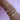 A wrist adorned with six bracelets on a pink background. Includes gold and pearl chains, a heart charm, and a gold cuff with sparkling accents, conveying elegance.