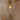  close-up view of a woman's neck showcasing two layered gold necklaces. The shorter chain features a heart-shaped pendant engraved with "11:11", while the longer chain holds a statement butterfly pendant adorned with sparkling clear crystals along the wings. The jewellery is styled over a white ribbed top, with natural light highlighting the gold tones.