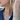 Model wearing silver heart earrings, charm necklace with cross and flower details, and custom BINKY BELLE name bracelets in silver and gold